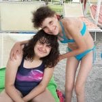 CasaOz - bambine sorridenti che si abbracciano in spiaggia